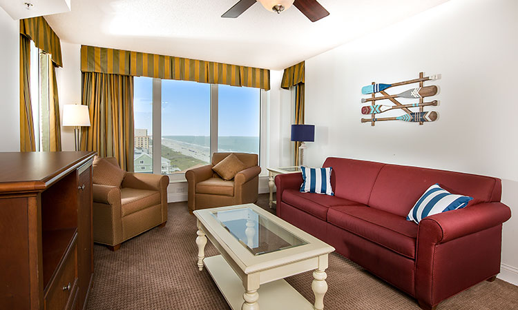 King bed and two full beds in a fully equipped condo with a side view of the ocean.
