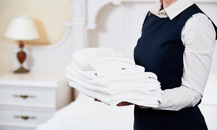 housekeeper holding towels in bedroom